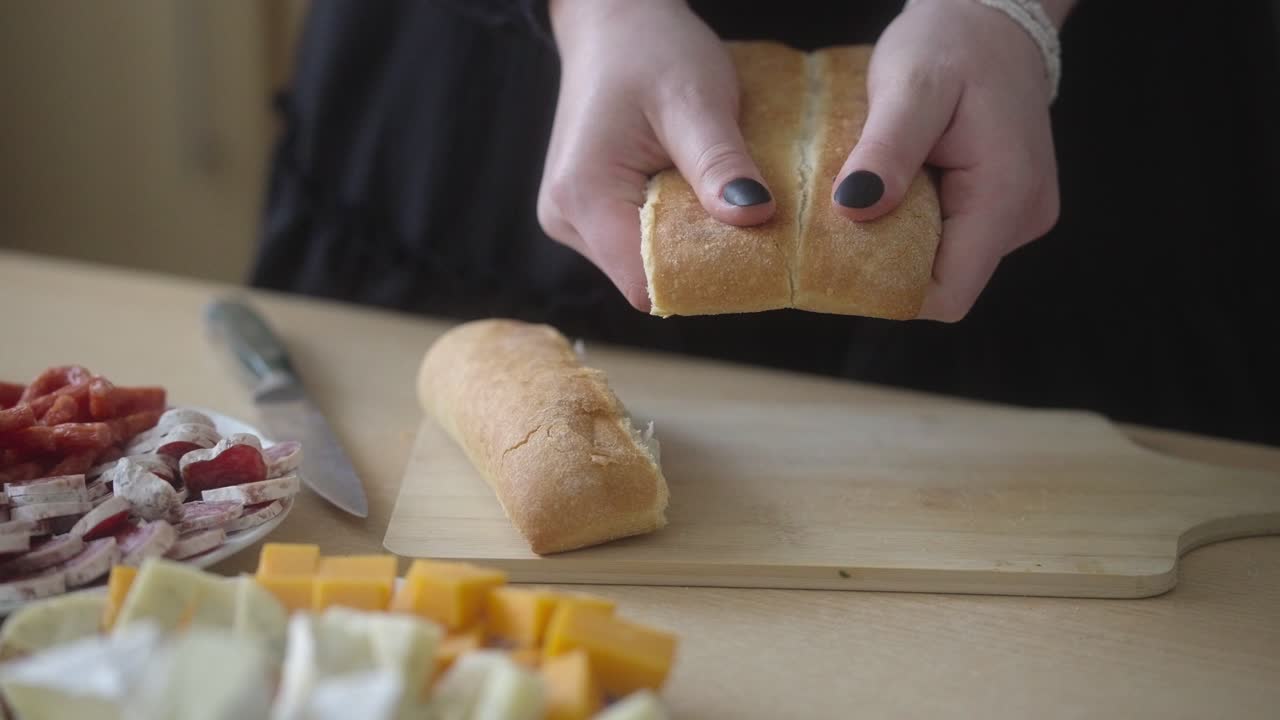 Sliced ​​white bread on the table. Food preparation by a young woman with black nails