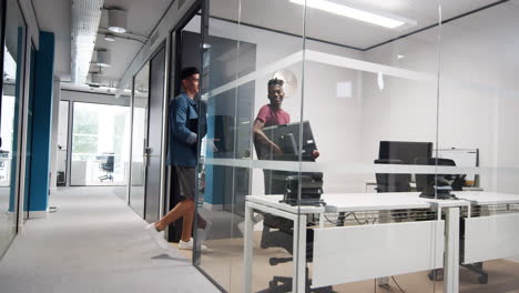 Two-young-men-carrying-computers-into-an-office-cubicle