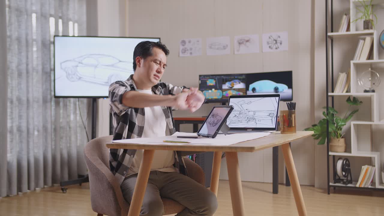 아시안 남성의 측면 뷰는 tv와 컴퓨터 디스플레이 3d 전기 자동차 모델을 가진 스튜디오에서 태블릿에 새로운 자동차 디자인 컨셉을 그리는 동안 스트레칭합니다.