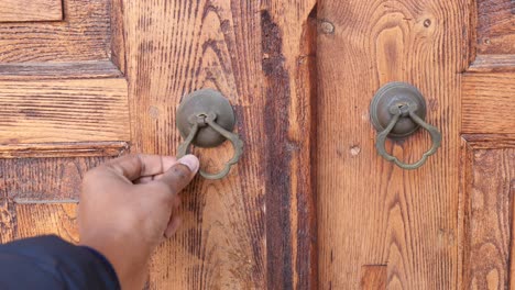 hand reaching for antique wooden door knocker