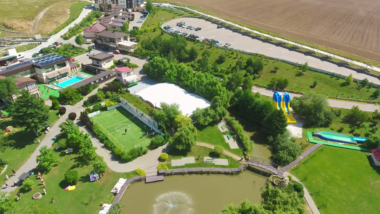 Recreational zone with private bungalows, swimming pools, tennis court and children playgrounds. People walking and resting in rural area. Top view.