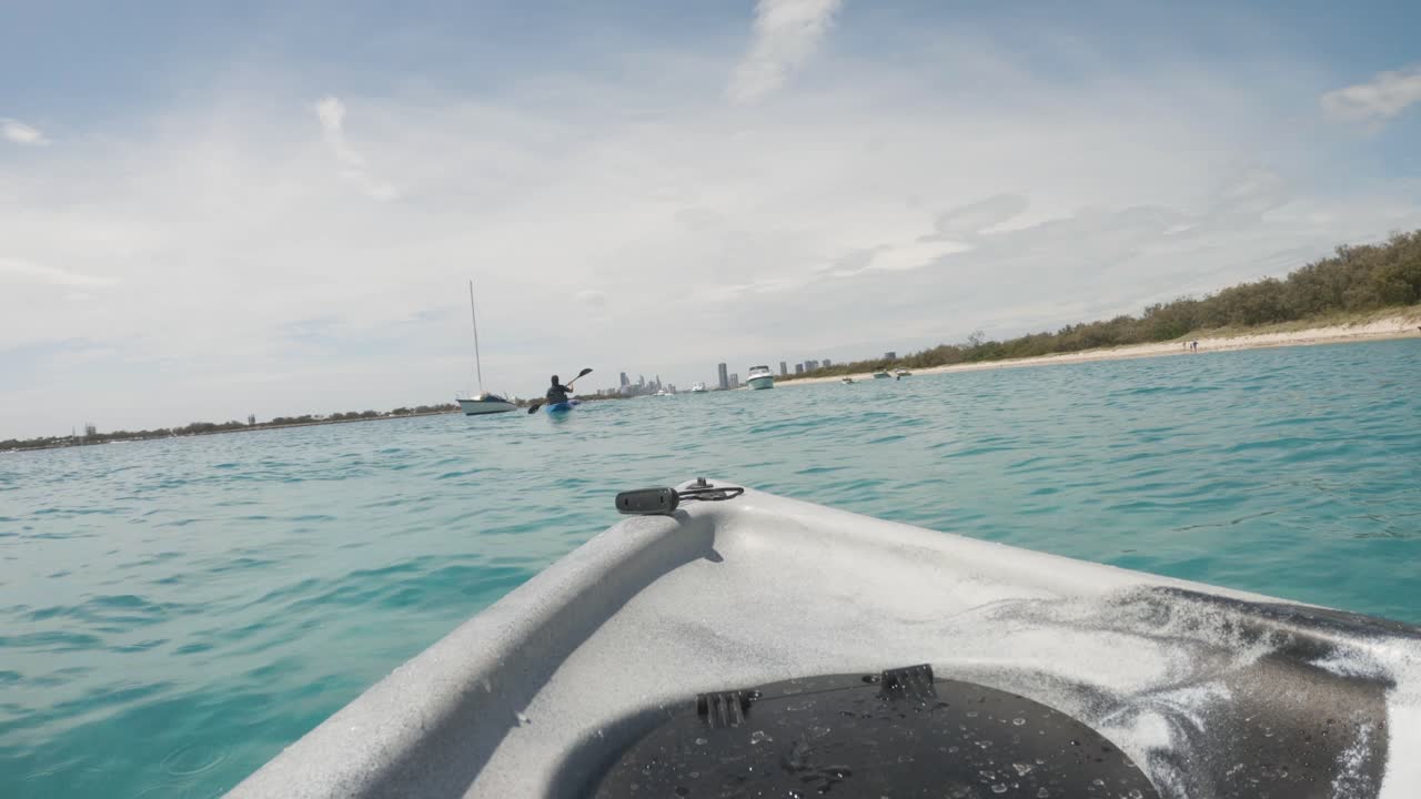 una pareja navegando en kayak en un puerto oceánico en un popular lugar de vacaciones hacia el horizonte de la ciudad