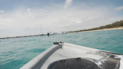 Una-Pareja-Navegando-En-Kayak-En-Un-Puerto-Oceánico-En-Un-Popular-Lugar-De-Vacaciones-Hacia-El-Horizonte-De-La-Ciudad