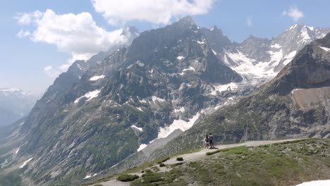 aerial orbit pullback reveals rugged alpine terrain and scenic views during a hike in the mont blanc region, featuring snow-capped mountains and meadows