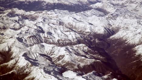 aerial plane view of snow covered mountain peaks of alps and alpine valleys