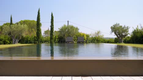 Low-Angle-Aufnahme-Eines-Reflexionsbeckens-Mit-über-Die-Seiten-Fließendem-Wasser-In-Einer-Villa