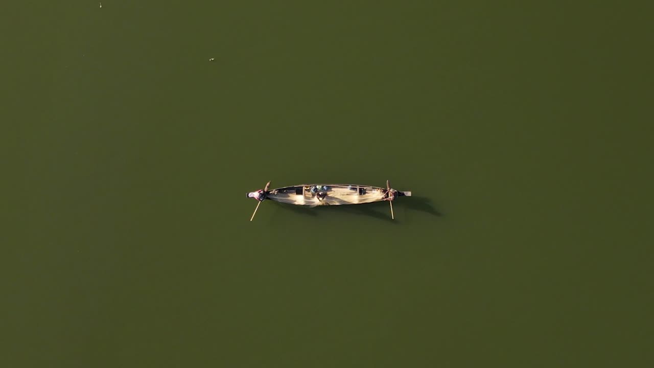 낚시 그물을 사용하여 물고기를 잡는 어부와 함께 호수에서 작은 나무 보트의 하향식 공중 샷