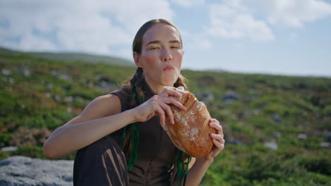 girl biting fresh bread on field closeup. hungry traveler enjoying tasty loaf