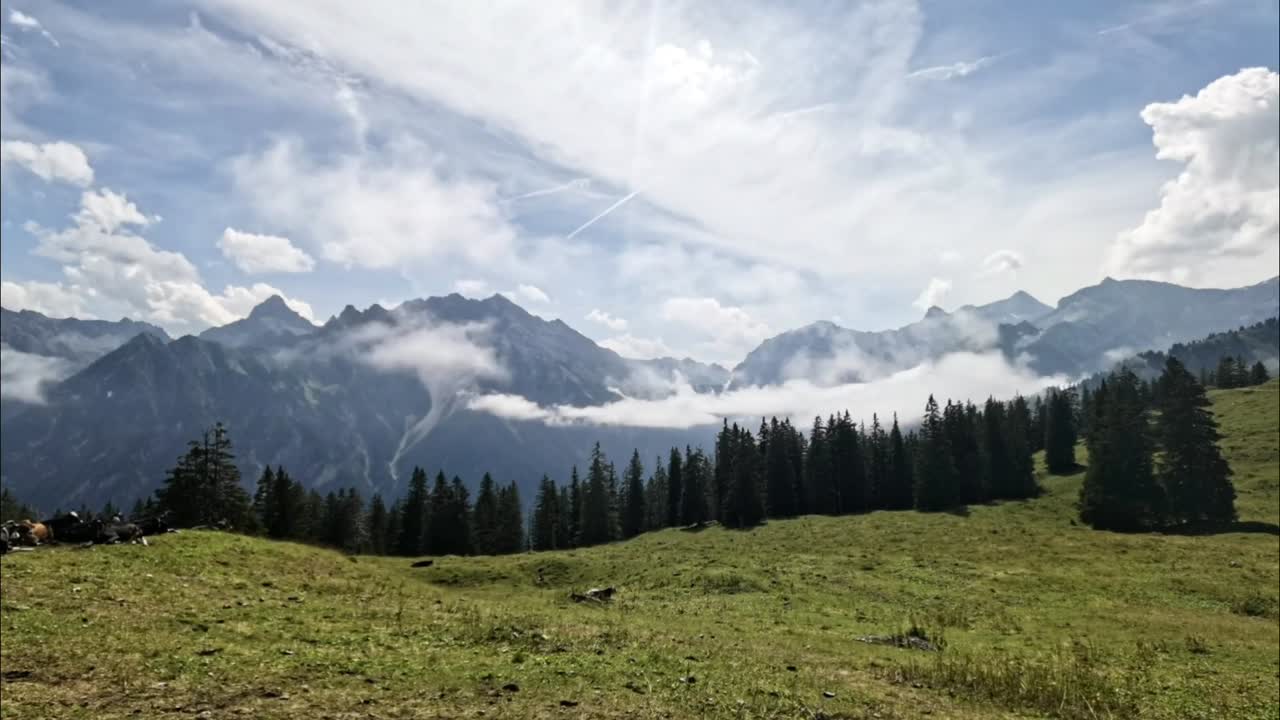 Časosběr mraků plujících nad malebnou horskou krajinou v rakouských Alpách v Evropě s pasoucími se kravami