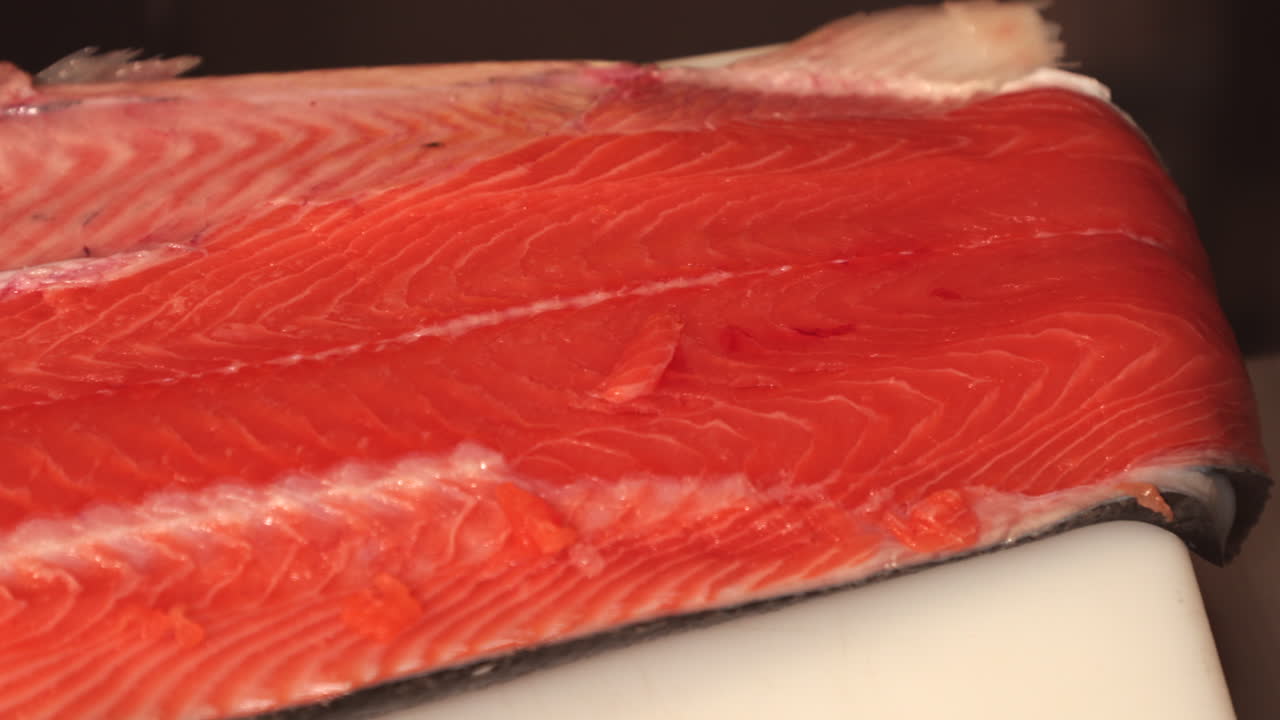 신선한 연어 필레는 초밥을 만들기 위해 부엌의 도마 위에 놓여 있습니다
