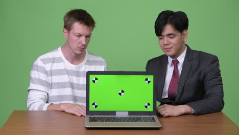 アジアのビジネスマンとスカンジナビアのビジネスマンがラップトップで一緒に働く