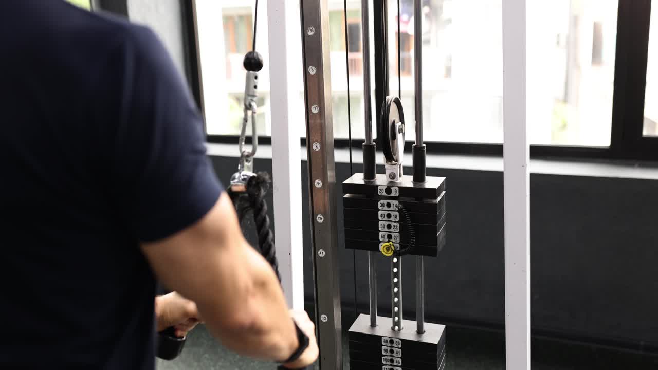 Person performing triceps workout on a cable machine in a gym