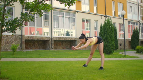 calentamiento de una atleta femenina que realiza pistas en el parque en el césped