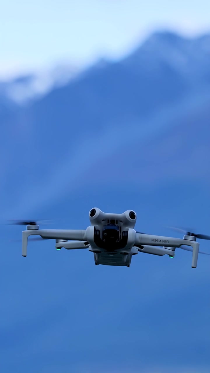 Quadcopter drone kameraya doğru sabit bir şekilde uçar, dağlar ve yumuşak gün ışığı dramatik bir dış mekan sahnesi yaratır
