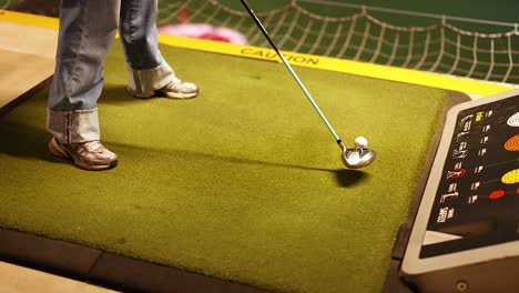 woman practicing golf at an indoor driving range