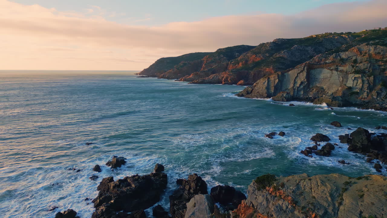 Rocky slopes meeting ocean aerial view. Tranquil waves washing cliffs shoreline