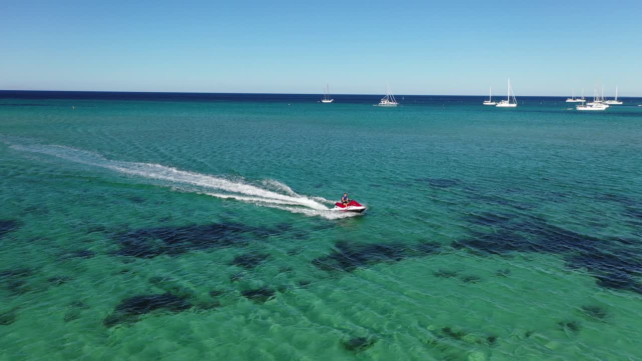 vista aérea, scooter de agua navegando en agua de mar turquesa cerca de la costa australiana en un día soleado de verano, disparo de drones en órbita