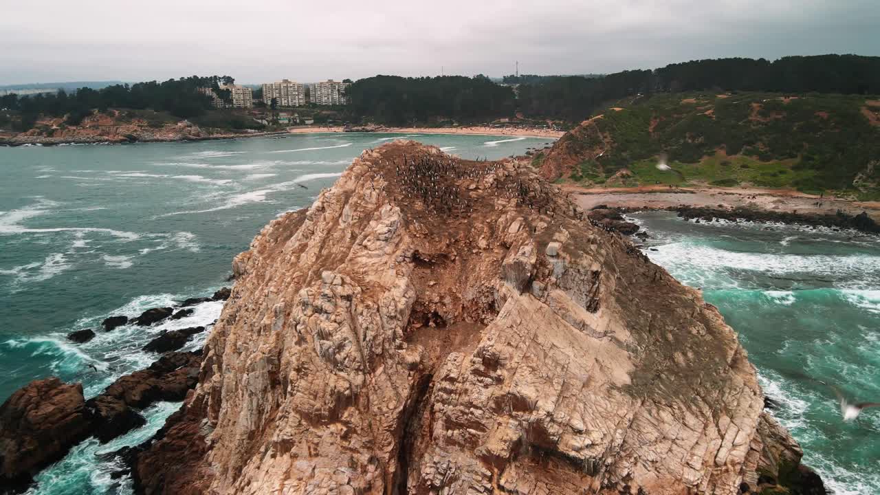 Drammatica ripresa aerea all'indietro con drone di una formazione rocciosa ad Algarrobo, Cile, costa dell'Oceano Pacifico con onde turchesi