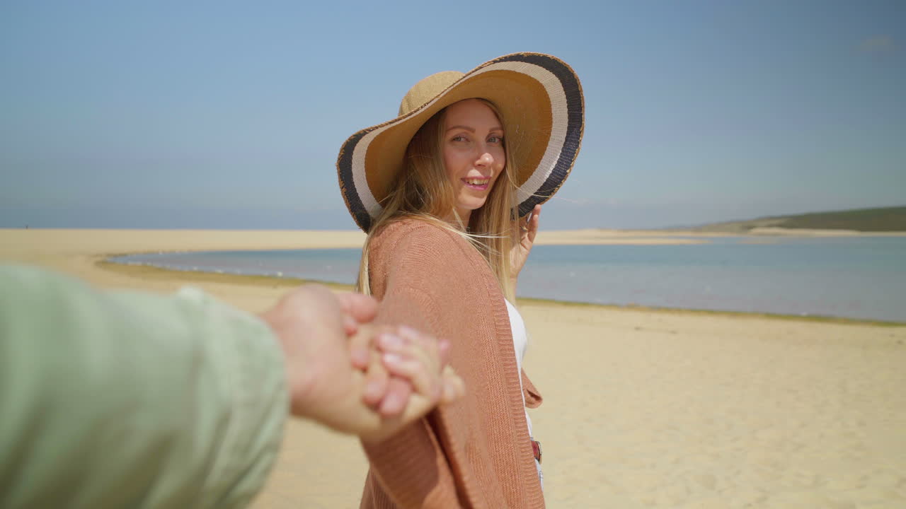 disparo recortado de una pareja caminando por una playa de arena