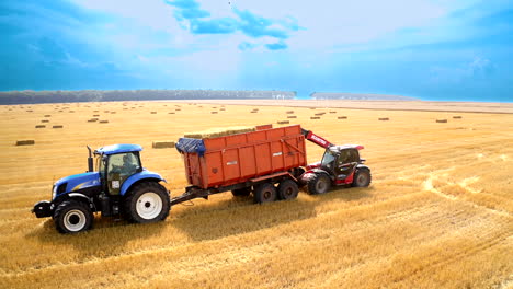 tractor picking up bales of straw hay. aerial drone view of collection of straw bales