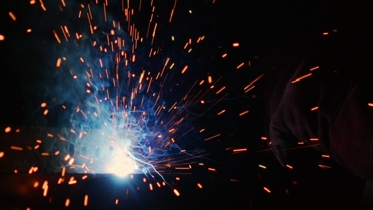 Close up of a welding arc, with sparks flying through the air.