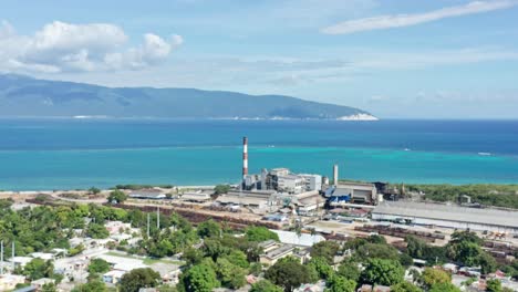 aerial view of sugar mill factory in front of tropical caribbean sea in background during sunny day - barahona,dominican republic