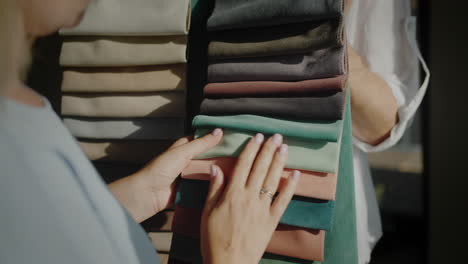 the buyer chooses the fabric in the textile store, the seller holds samples with multi-colored fabric