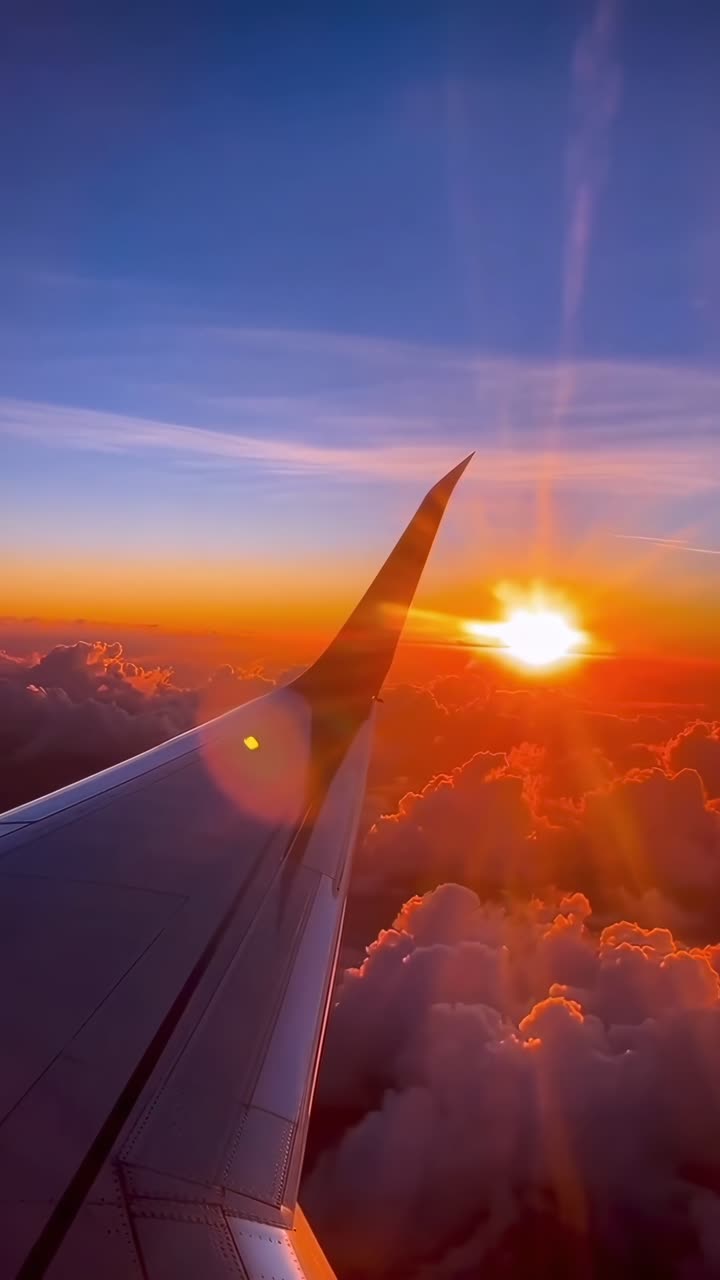 Video aéreo de un ala de avión al atardecer, capturando cielos vibrantes y nubes esponjosas.