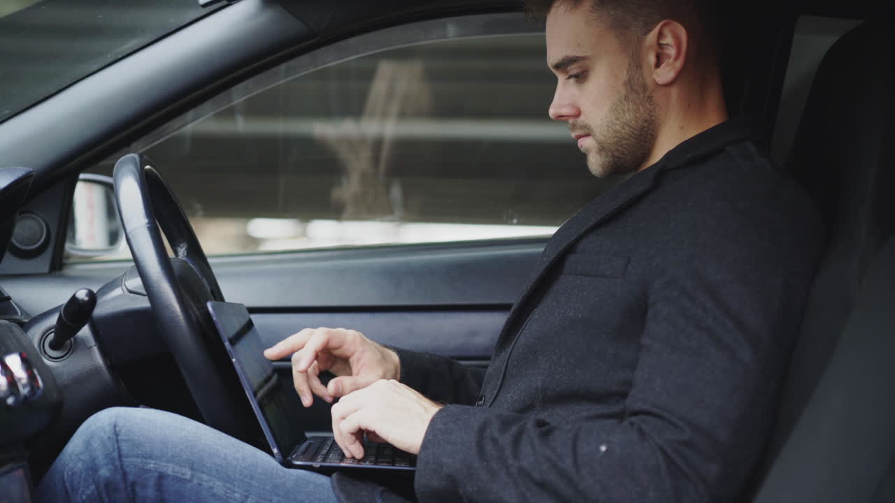 Man working on laptop in a car
