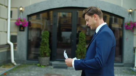 side view man reading document at street. guy reading bad news from data outside