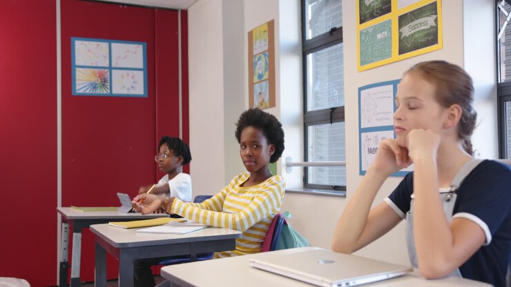 In school, three girls sitting at desks, listening attentively in classroom