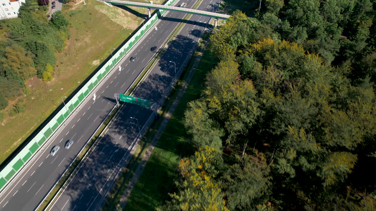 위 에서 아래 로 - 도로 가장자리 에 있는 나무 들 근처 에 있는 빠르게 움직이는 도로 위 에 있는 항공기 - 그디니아, 폴란드
