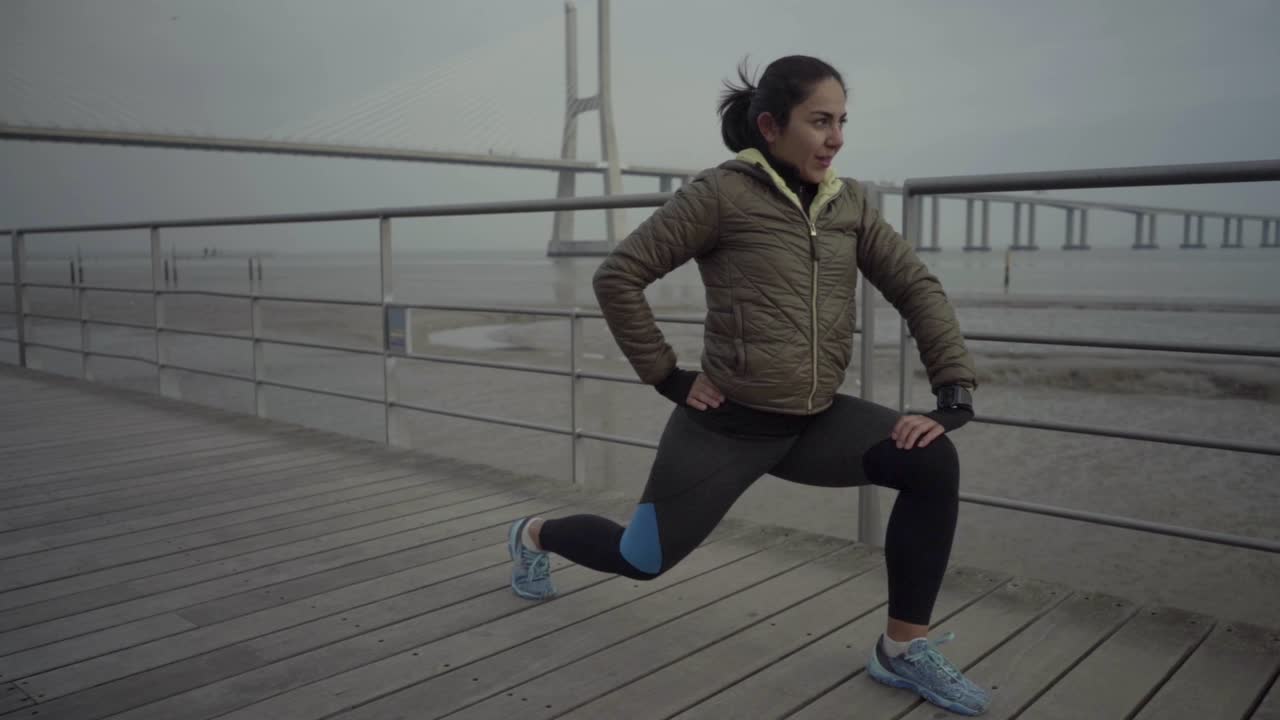Smiling sportswoman stretching legs before training