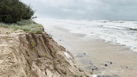 a series of frames showing beach erosion and rough waves during cyclone alfred, highlighting environmental impact and stormy weather