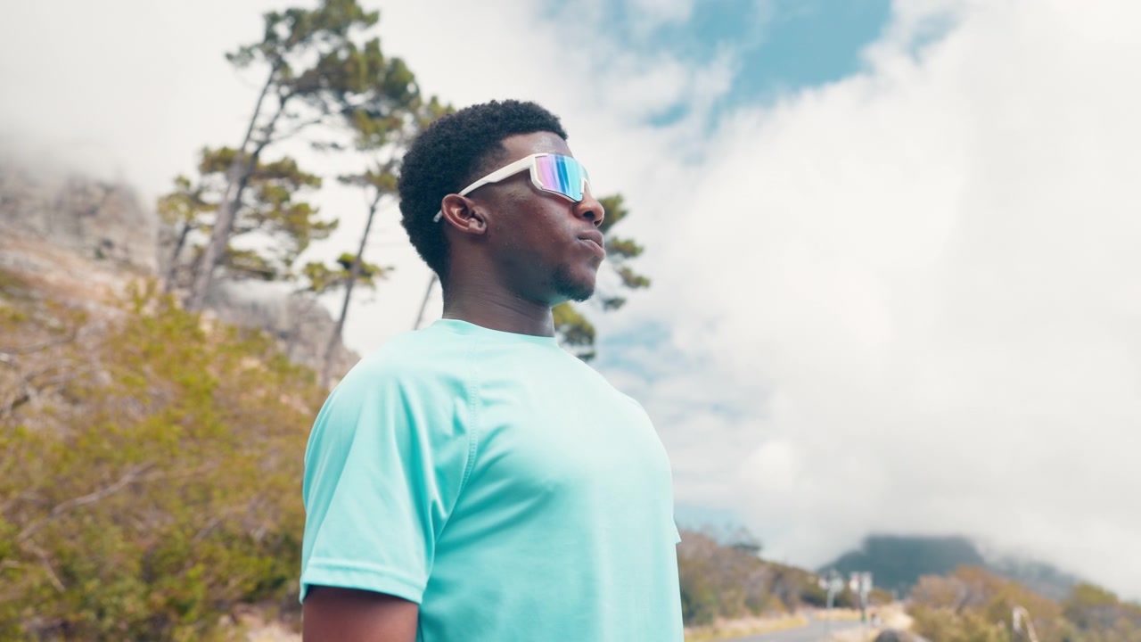 Young Man Putting on Sports Sunglasses Outdoors