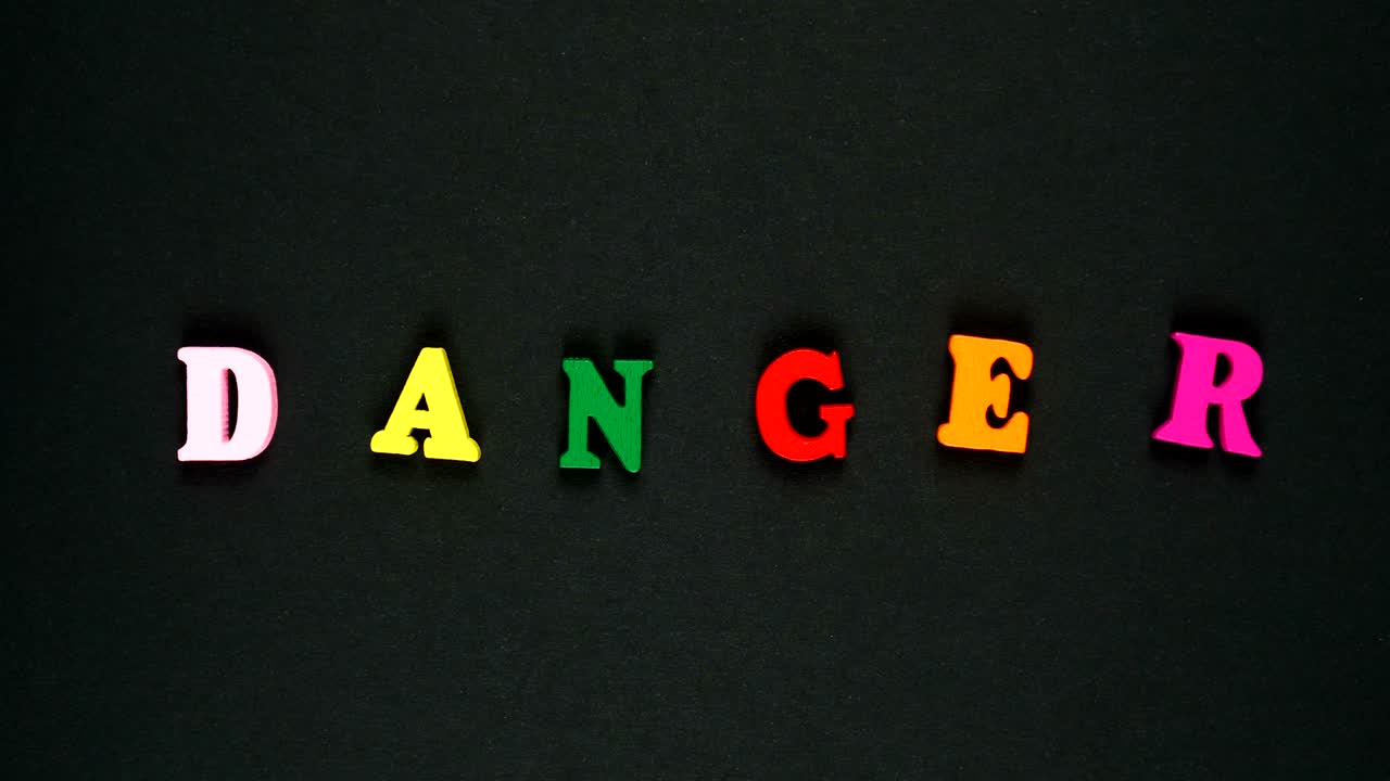 나무로 만든 다채로운 글자로 구성된 단어 위험. 다채로운 단어 루프. 스 모션 애니메이션.