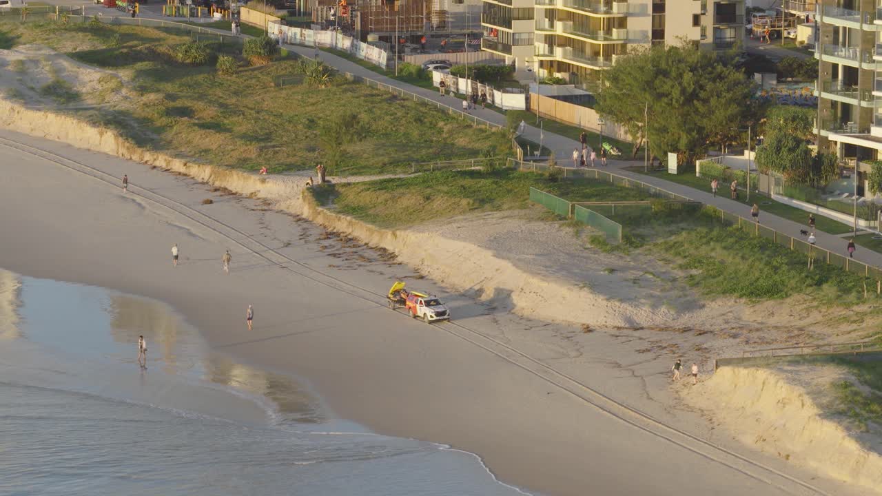 Aerial view of a beach patrol vehicle on Gold Coast, Australia. Captured during sunset with a serene coastal environment