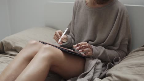 woman drawing on a tablet in bed