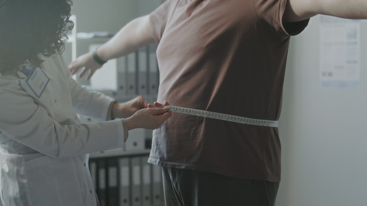 Medico che misura la circonferenza vita di un paziente
