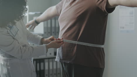 doctor measuring waist circumference of a patient