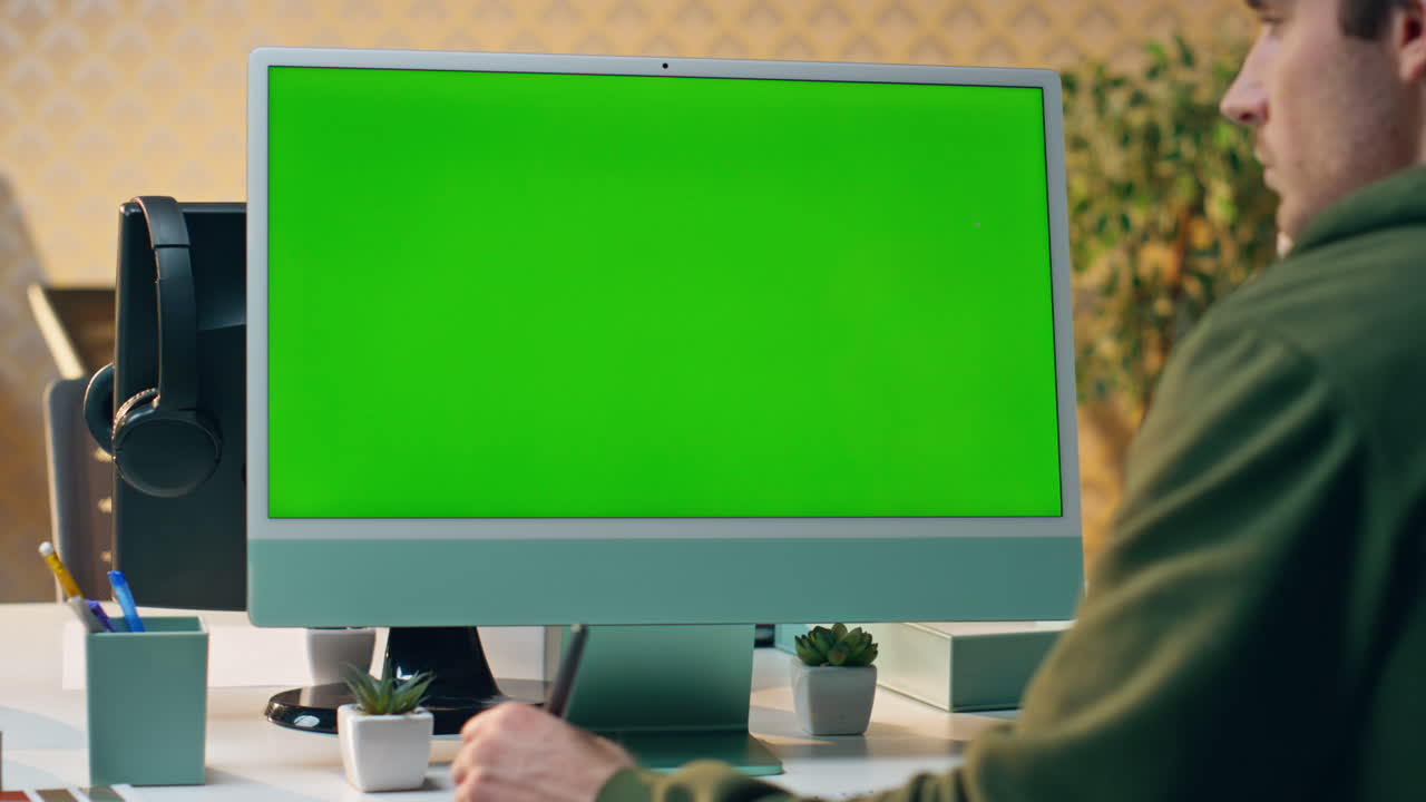 artista focalizzato a fissare la schermata verde creando il tablet da vicino. progettista che lavora