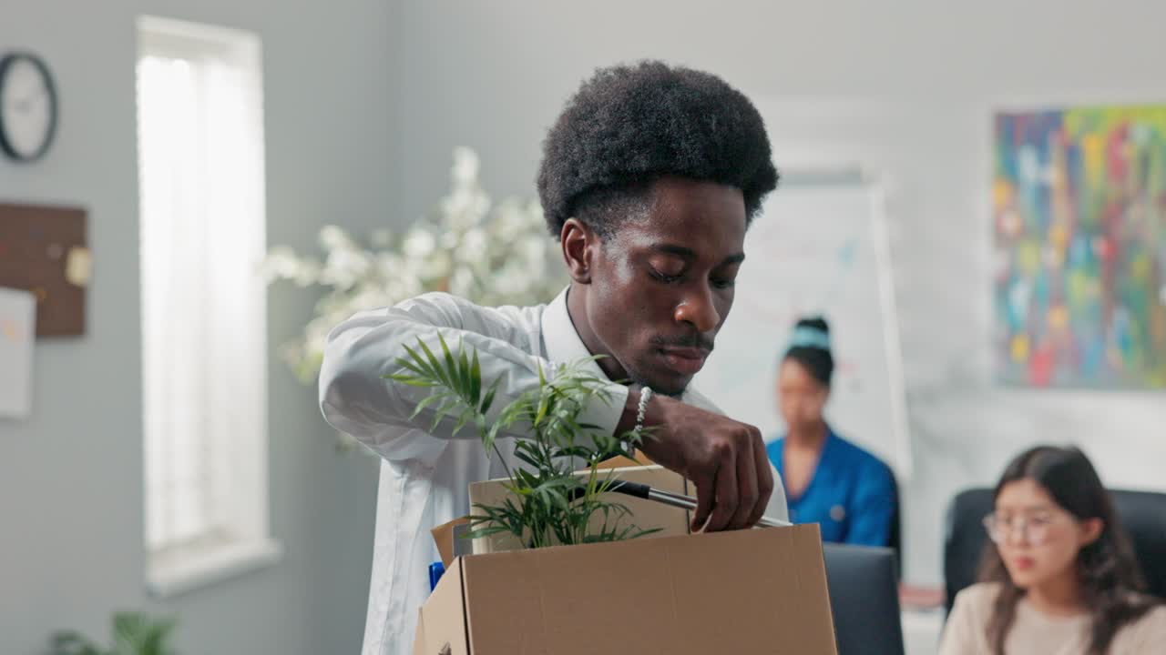 Man with afro hair quits corporate job leaves office with things packed in box leaves corporate, checks to make sure he took everything, quits job, retires, happy smiling
