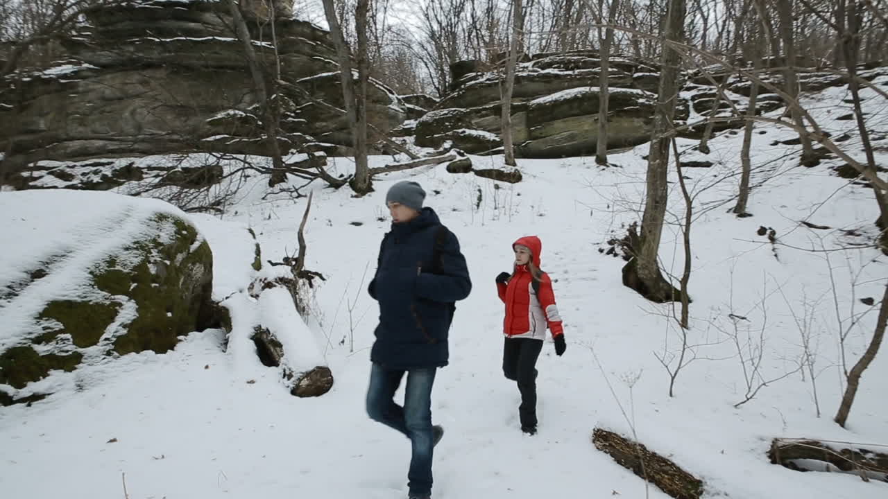 Couple hiking with backpack on snow trail forest