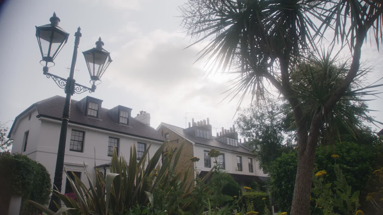 전면에 식물과 잎사귀가 있는 런던 시의 특이한 집의 넓은  ⁇