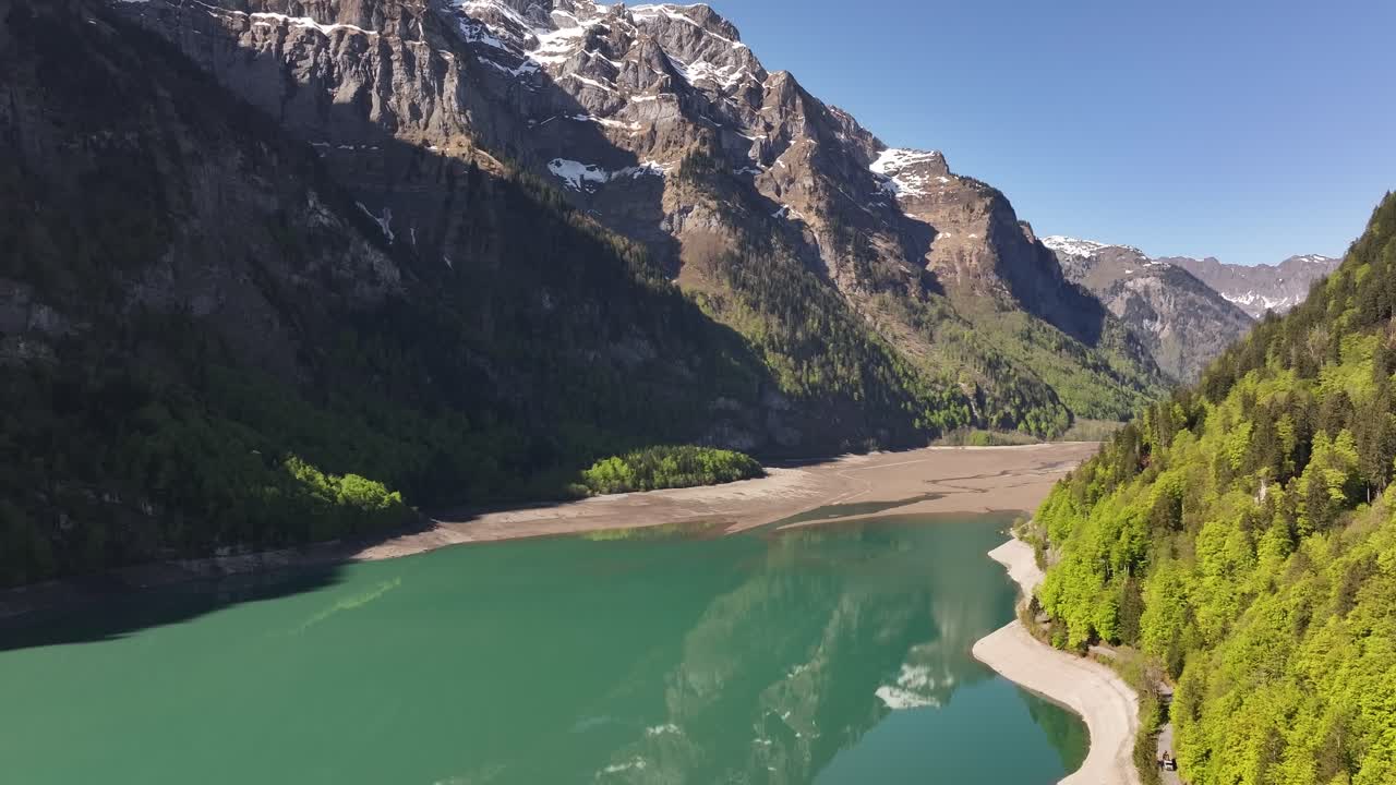 Klöntalersee in Glarus, Switzerland aerial drone view clear turquoise lake, green forest and snow mountains