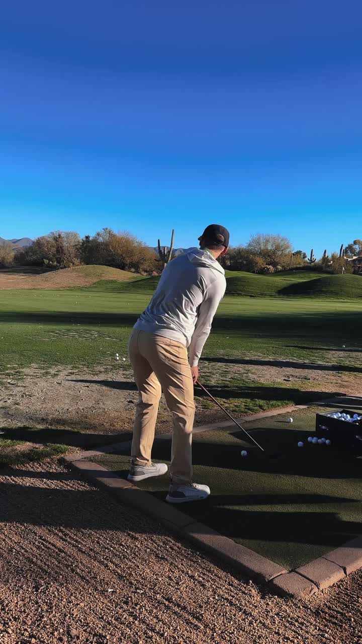 Golfçü, çöl golf sahasında gün doğumunda sürüş alanında hibrit vuruş yapıyor, akıcı vuruş dikey 4k güneşli gün