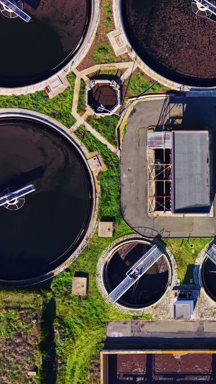 Top down aerial view of round secondary clarifiers and rectangular basins at a wastewater plant. Circular sedimentation tanks at treatment facility. Vertical video