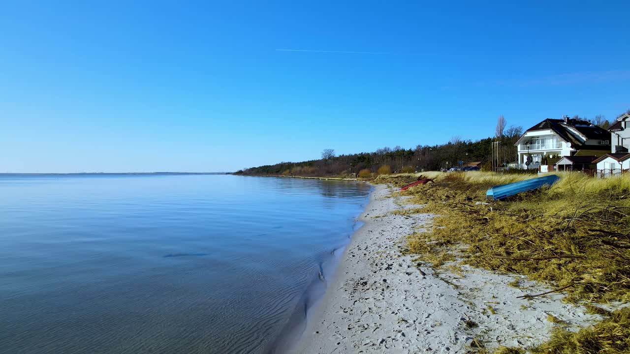 tranquilamente ondeando el agua del lago azul claro en una pequeña playa de arena con enormes villas de lujo con hermosas vistas en un claro día de verano en polonia
