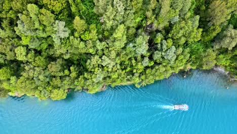 Overhead-truck-right-of-a-boat-with-people,-sailing-along-the-shore-of-Lake-Todos-Los-Santos,-southern-Chile