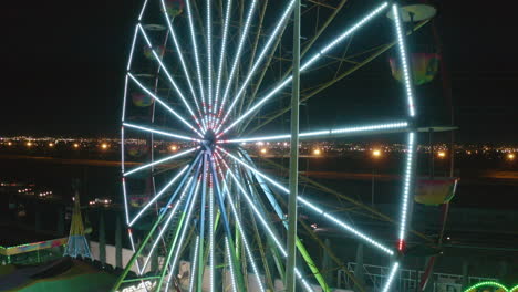 drone of an unfilled carousel at a carnival with flickering multicolored lights